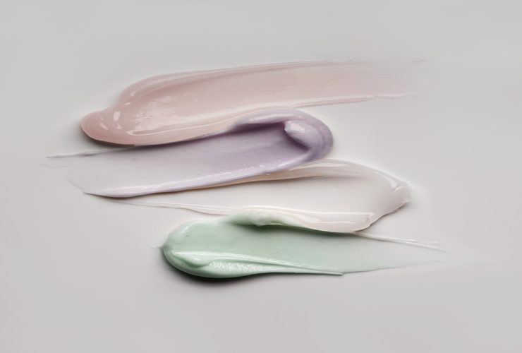 Transparent or yellow, mint green and purple pink colored cosmetic body or face gel cream mask on white and multi-colored texture background